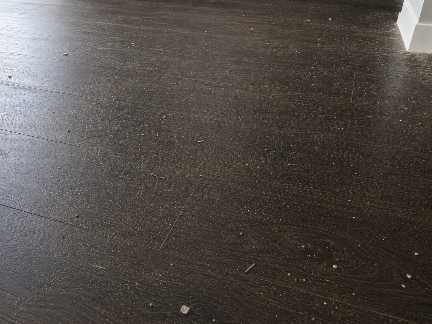 Dark timber floor with dust and loose construction debris before cleaning