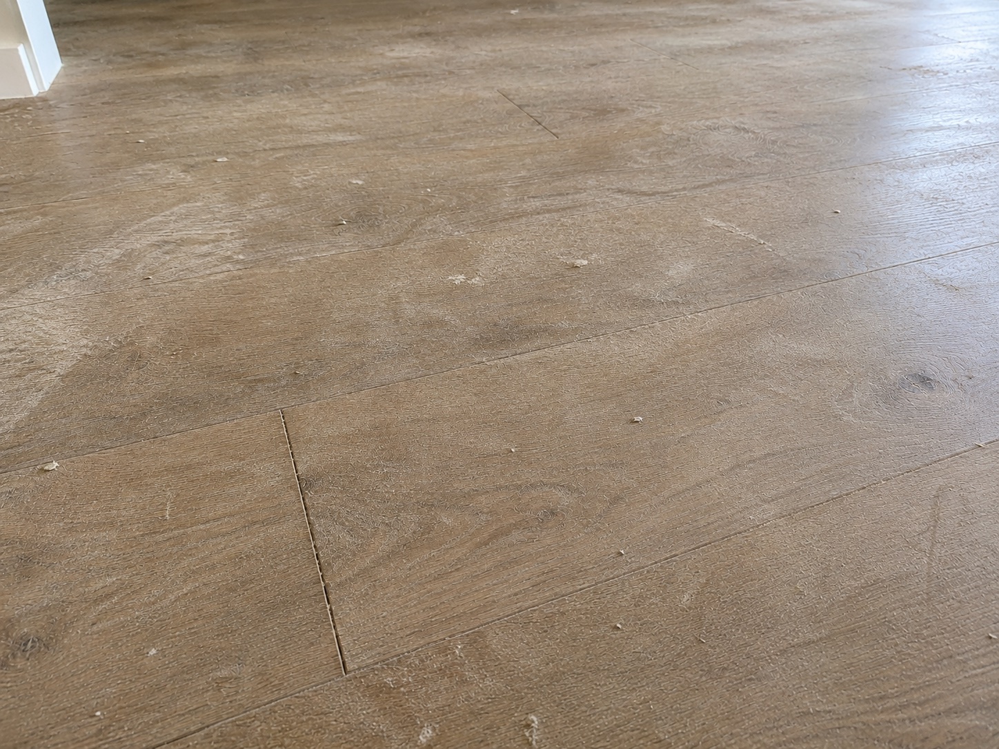Light timber floor with footprints, dust and construction offcuts before cleaning