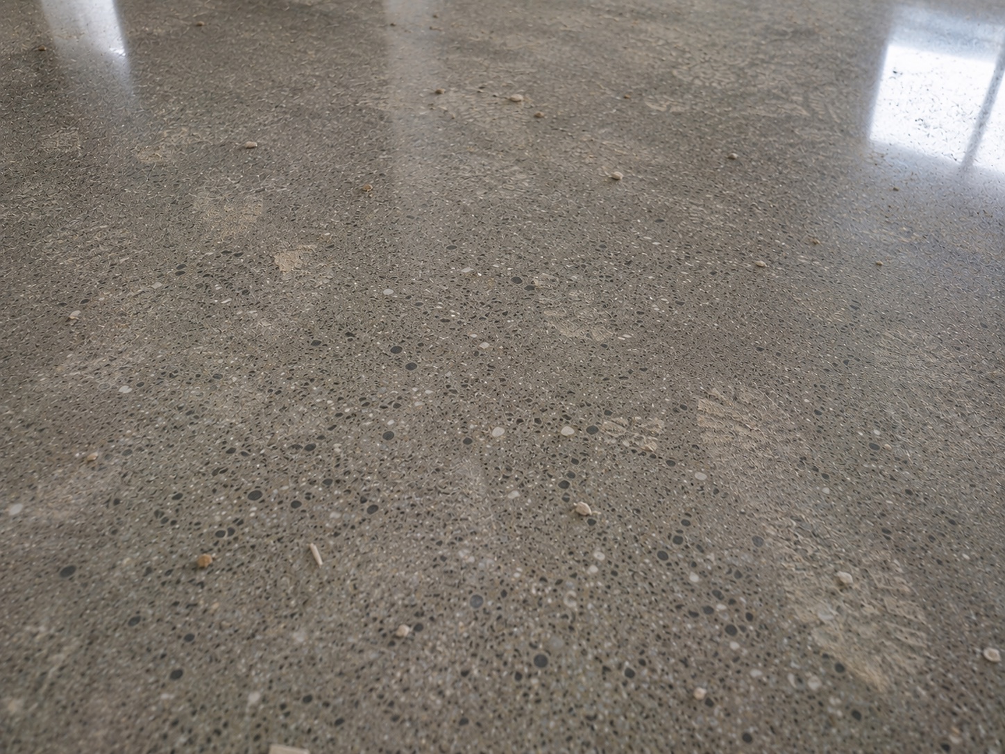 Polished concrete floor with building residue and loose debris before cleaning