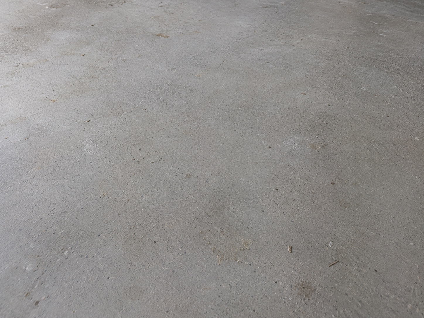 Raw concrete floor with construction dust, marks and loose debris before cleaning