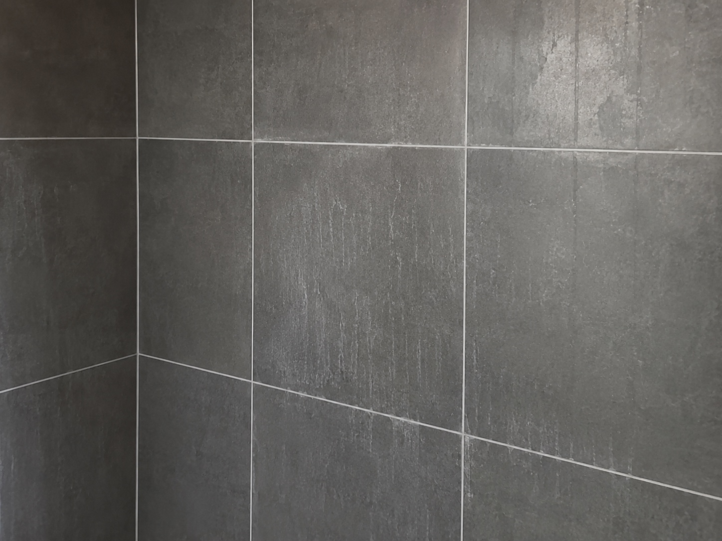 Bathroom wall tile with residue and streaking before scrubbing