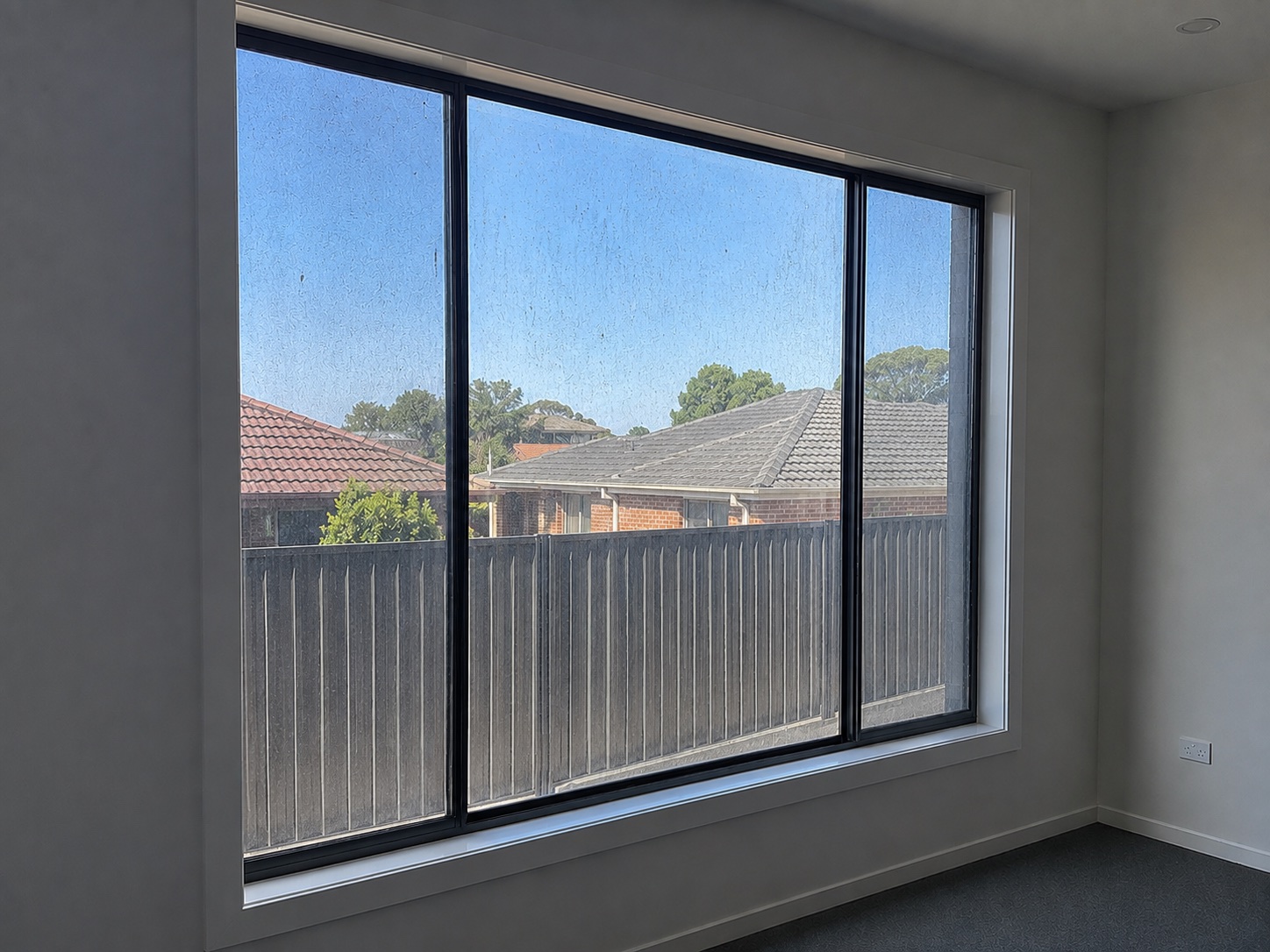 Internal new-build window marked with plaster dust and site residue before cleaning