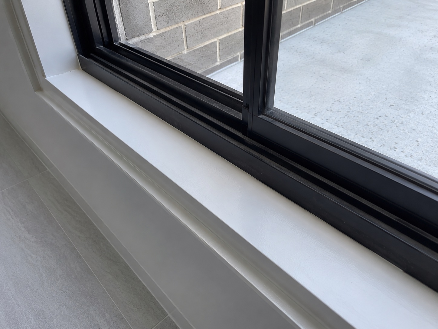 Clean black aluminium window track and white sill after builders cleaning